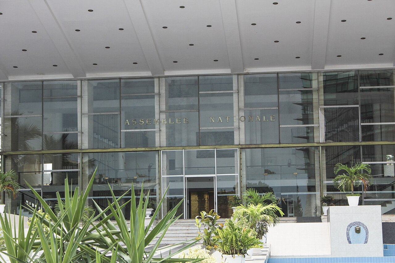 The National Assembly building in Dakar, seen through trees beneath a pale sky.